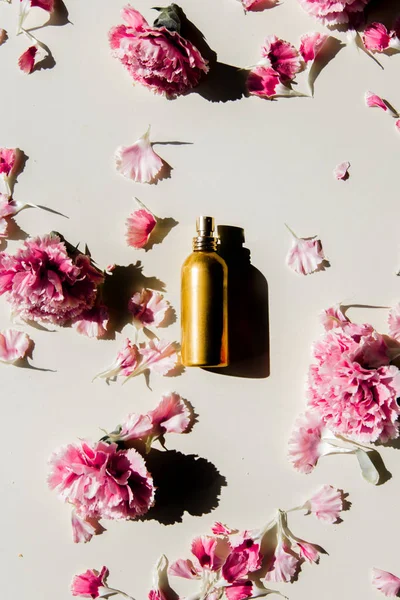 Płatki Dianthus i butelka perfum z naturalnymi cieniami — Zdjęcie stockowe