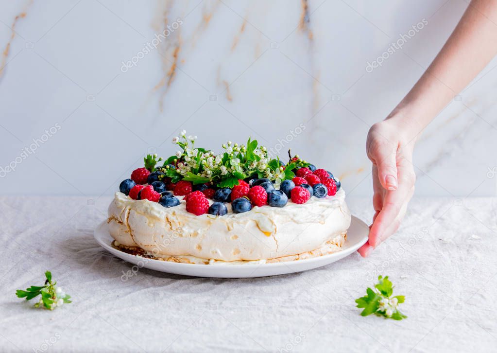 female hands of the pastry chef decorate cream pie with branches