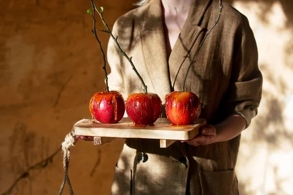 woman hold in hands apples in caramel with branches