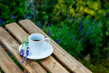 Lavanta bahçesinin yanındaki ahşap masada bir fincan espresso kahvesi.