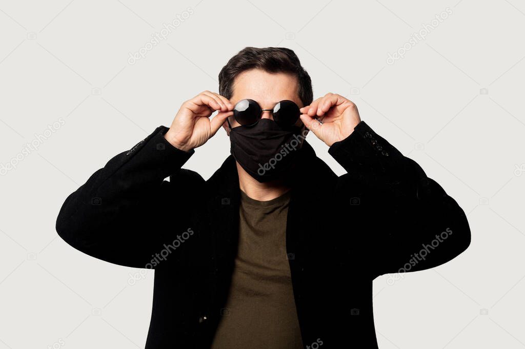 Style guy in black coat, face mask and sunglasses 