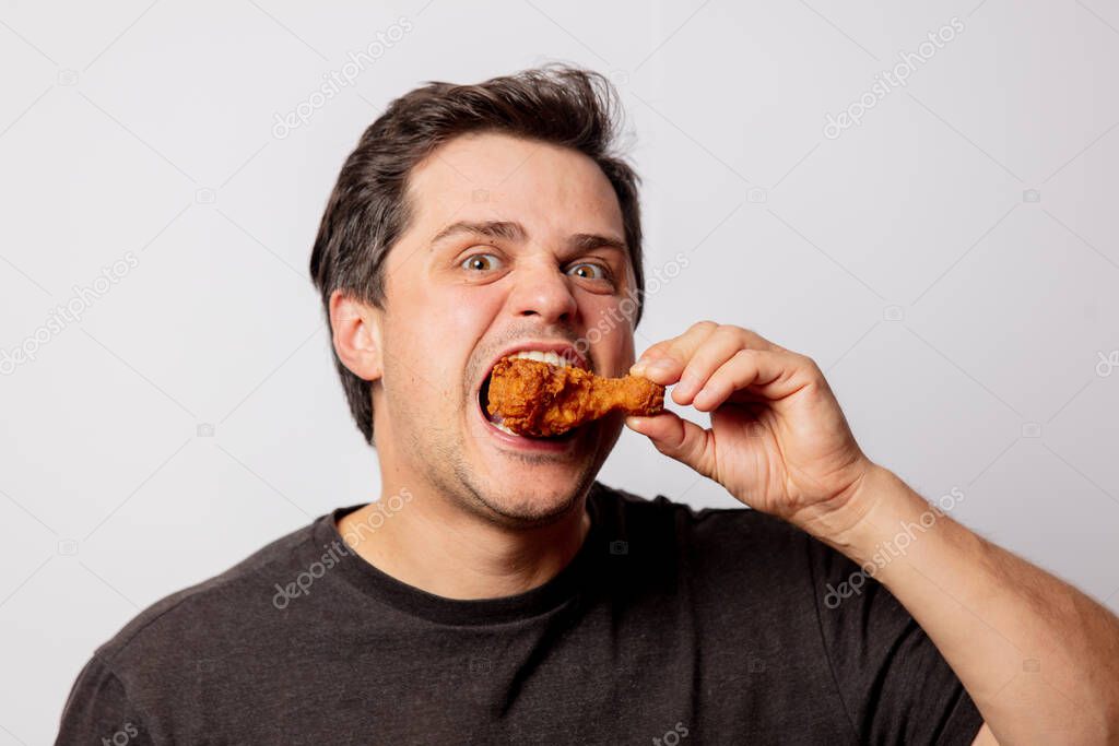 White man in black shirt with chicken drumsticks on white background