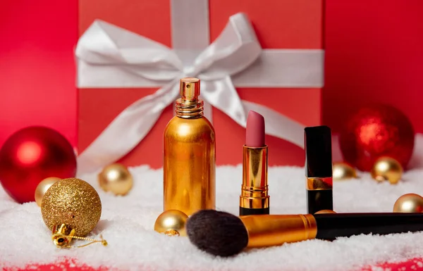 赤い背景に化粧品と雪のクリスマスボックス — ストック写真