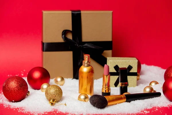 Weihnachtsschachtel Mit Kosmetik Und Schnee Auf Rotem Hintergrund — Stockfoto