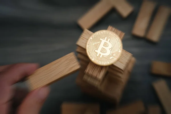Ahşap yapı taşları kuleye bir blok hareket el ile Bitcoin. Bulanıklık etkisi zoom. Bitcoin risk kavramı.