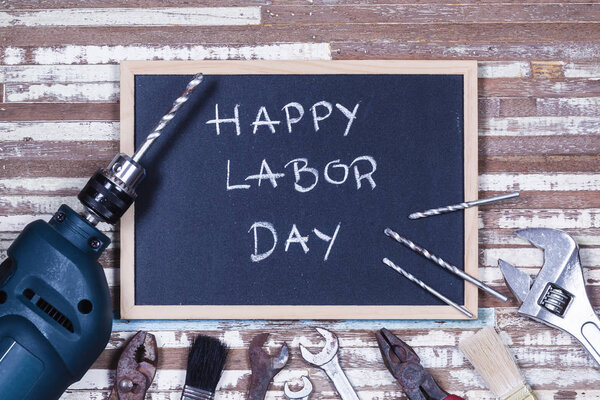 Chalk board with text HAPPY LABOR DAY with variety gruge rusty handy tools on a rusty wooden table.