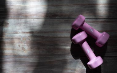 Aktif fitness yaşam tarzı ve egzersiz arka plan kavramı. Pembe dumbbell ahşap ışık ve gölge ile. Üstten görünüm.