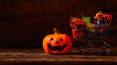 Cadılar Bayramı festival alışveriş kavramı. Halloween pumpkins ahşap arka plan üzerinde alışveriş sepeti ile.