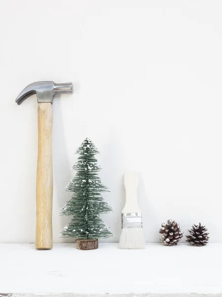 Merry christmas and Happy New year with handy tools background concept, hammers and paintbrush with Christmas tree and pine cones decoration on wood with copy space.