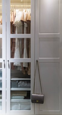 Şık çanta ve kapalı giysiler ile dolap. Kutuları ile beyaz gardırop Ray üzerinde asılı elbiseleri.