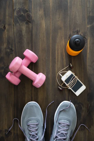 Fitness, healthy and active lifestyles Concept, dumbbells, running shoes, bottle of water, smartphone with earphone on wooden background. Top view with copy space for text.