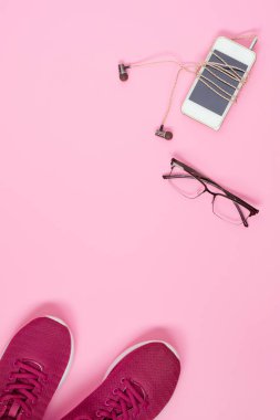 Spor ayakkabı, smartphone, gözlük ve kulaklık üzerinde pembe hamur
