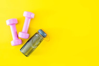 Sarı backgro üzerinde pembe dumbell ve şişe suyu Üstten Görünüm