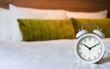 Yatak odasında vintage beyaz çalar saat. Alışveriş zamanı arka plan c