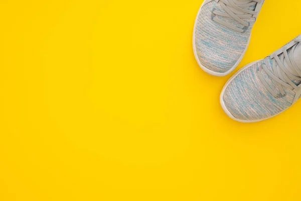 黄色の背景に女性のスポーツスニーカーのペア。トップビューウィット — ストック写真