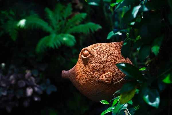Декоративная глиняная рыбная статуя, украшенная в тропической зелени — стоковое фото