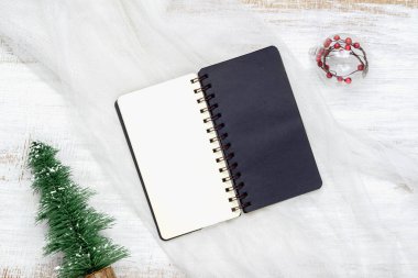 Yuva kumaşı ve beyaz ahşap arka plan üzerine boş defterin üst görünümü