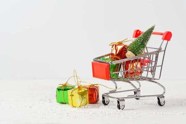Carrinho de compras com árvore de natal e caixas de presente em miniatura em wo — Fotografia de Stock
