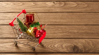 Üstünde Noel ağacı ve minyatür hediye kutuları olan alışveriş arabası.