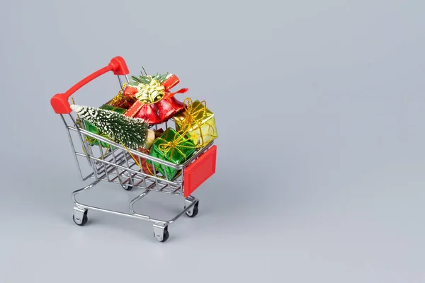 Shopping vagn med julgran och miniatyr presentförpackningar på gr — Stockfoto