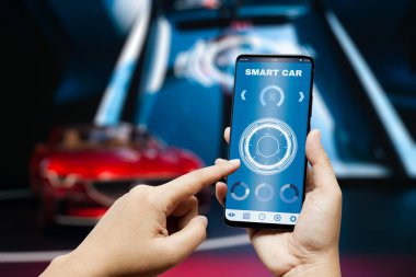 Akıllı araba uygulaması arka plan kavramı. Arkaplanı bulanık spor arabalı akıllı telefon ve uygulama paneli. Akıllı araba konseptindeki şeylerin interneti.