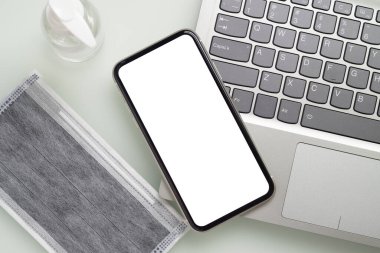 Coronavirus için beyaz ekranlı akıllı telefon. Salgın salgını önleme konsepti. Cep telefonunu laptopla, maskeyle, algohol jeliyle taklit et..