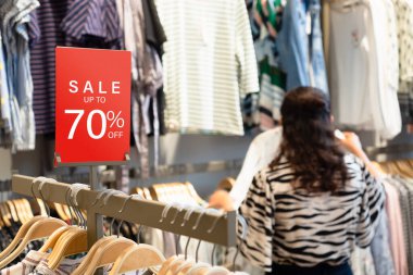İndirimli etiket, kadın giyim mağazasındaki raflarda duruyor. Kara Cuma ve Bayram sezonu satışları için indirim bilgileri ve tanıtım için. Sale Banner şablon modeli. Alışveriş merkezinde indirimli satış% 70 kırmızı tabela.