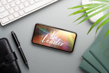 Lider olmak ilham verici bir geçmiş kavramı. Be Leader metninin düz görünümü, çalışan ofis masasındaki Smartphone 'da yatıyordu.