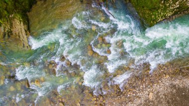 Islak kayalar ve çakıl shore ile dağ nehir rapids tepeden dron görünümü