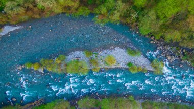 Islak kayalar ve çakıl shore ile dağ nehir rapids tepeden dron görünümü