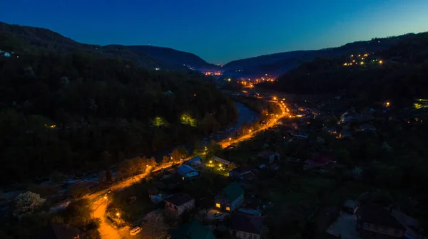 Drone view of mountains and illuminated road in the Plastunka village in the valley of the Sochi river at dusk, Sochi, Russia