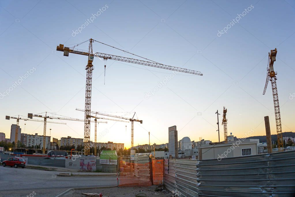 Construction site with cranes agains sunset. Wide angle horizontal image.