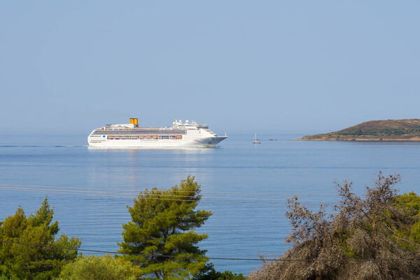 Big white overseas cruise ship in Ionian sea in Greece. Wide angle image with surroundings.