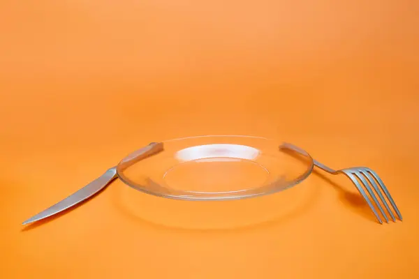 Посуда Вилка Нож Стеклянная Тарелка Оранжевом Фоне Широкий Угол Обзора — стоковое фото