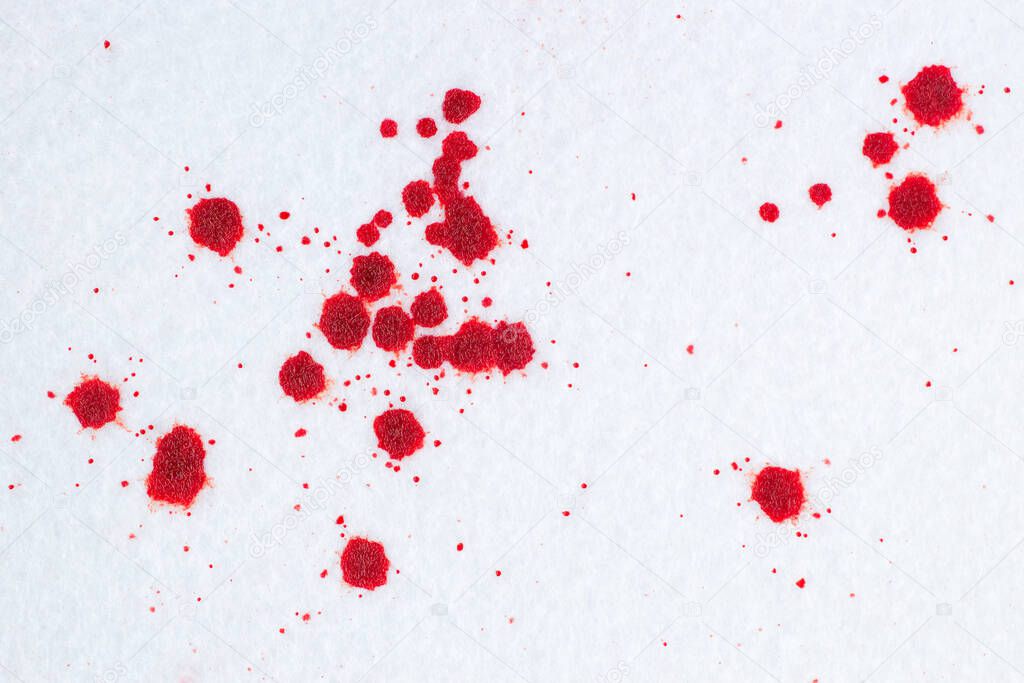 Red blood drops on white snow-liked felt background. Criminal or violence concep
