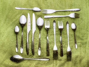 Yeşil havluda ıslak çatal bıçak takımı. Üst görünüm