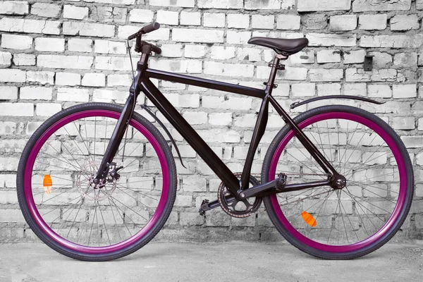黑色固定城市自行车 紫色的呼噜声映衬着黑色和白色的砖墙 — 图库照片