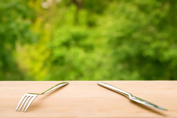 Πιρούνι Και Μαχαίρι Ξύλινο Τραπέζι Φόντο Πράσινο Φύλλωμα Καλοκαίρι Εξωτερικό — Φωτογραφία Αρχείου