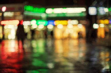 Uzaktan çözünmüş dükkanların camları ve yansımaları ıslak kaldırıma. Bulanık arkaplan