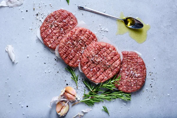 ローズマリー 灰色のテーブル上の種が付いているハンバーガーを作るため生の有機ひき牛肉パティーを上記表示します — ストック写真