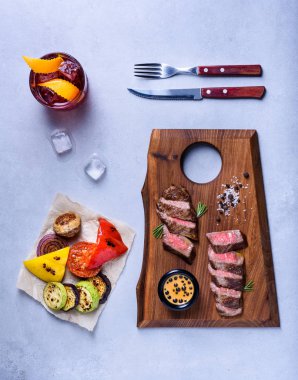 Izgara sebze ve içki ile ahşap tahta üzerinde orta Dana kaburga biftek dilimleri. Üstten görünüm