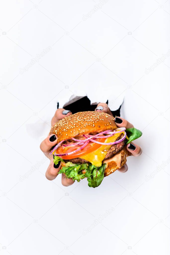 Hands holding cheeseburger with beef cutlet. Close up, Fast food. White background.