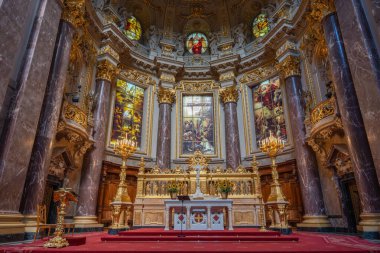 Berlin Katedrali 'nin merkezi sunağı zengin bir şekilde süslenmiş. Altın şamdanlar ve boyalı cam heybetli bir atmosfer yaratır..
