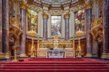 Berlin Katedrali 'nin ana mihrabında altın detaylar ve kırmızı halı var. Lekeli cam resimler kutsal güzellikler katar..