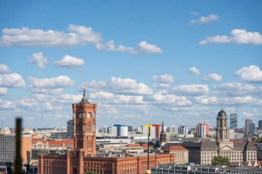 Red Town Hall ve Skyline. Kızıl Kasaba Binası 'nın kulesi Berlin siluetine karşı duruyor. Arkasında da rengarenk binalar ve hareketli binalar vardır..
