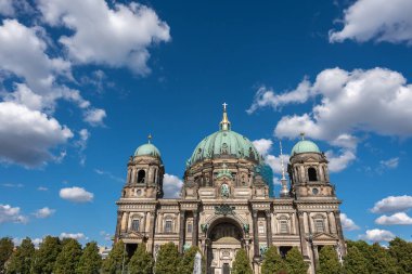 Bulutlu Gökyüzü ile Berlin Katedrali. Berlin Katedrali bulutlu mavi bir gökyüzünün altında heybetli görünüyor. Ağaçlar ibadethane çerçevesi.