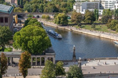 Almanya 31 Ağustos 2025. Spree boyunca büyük bir gezi teknesi yelken açar. Arka planda bankalar boyunca parklar ve yürüyüş yolları var..