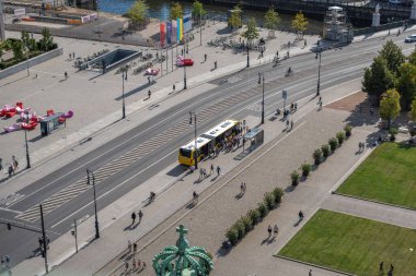 Almanya 31 Ağustos 2025. Yolcular inip inerken, sarı şehir otobüsü otobüs durağında durur. Yayalar ve bisikletçiler cadde boyunca ilerliyorlar.