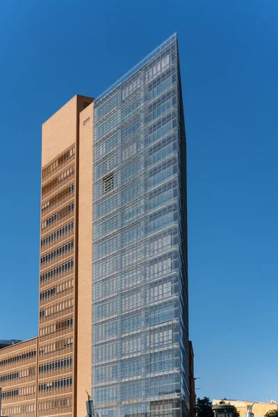 Gökyüzüne cam cepheli modern bir gökdelen yükseliyor. Temiz mimari zarif ve kentsel bir görünüm yaratır..