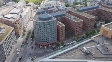 Berlin 'in modern ofis binaları ve caddeleri yukarıdan görülüyor. Arabalar ve yayalar şehrin şehir ritmini gözler önüne sererek aşağı iniyor..
